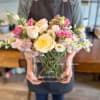 A soft, blush arrangement in pinks and cream featuring roses, lisianthus, mini