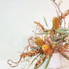 - Unique arrangement featuring yellow banksias and kiwi branches
- Delicate white accents