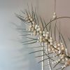 - Circular hanging floral arrangement with graceful palm frond
- Intertwined with delicate