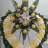 Open heart with white and yellow carnations, yellow roses, and white lilies.