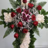 Cross with white carnations, red roses, and purple lilies.