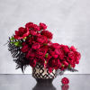 A modern ceramic vase, 7 inches in diameter, filled with lush red