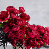 A modern ceramic vase, 7 inches in diameter, filled with lush red