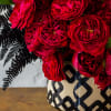 A modern ceramic vase, 7 inches in diameter, filled with lush red