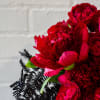A modern ceramic vase, 7 inches in diameter, filled with lush red
