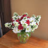 A whimsical bouquet of daisies, asters, and red mini roses are designed