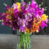 A clear glass vase filled with beautiful shades of vandela orchids.