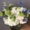 Fresh summer arrangement with hydrangeas. roses, delphiniums, misty, and green in clear