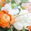 A hand-tied arrangement includes roses, hydrangeas, freesias, and ranunculus.