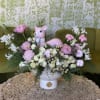 This enchanting Christmas arrangement features Peonies, Lilies, and Roses, complemented by seasonal