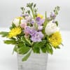 This arrangement reflects the light, soft color palette of pink, lavender, and
