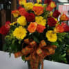 Variety of colored roses, Gerbera Daisies, Solidago in a clear vase with