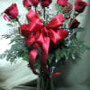 Gorgeous, premium red roses arranged in a glass vase with lush fern