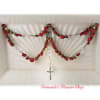 The image displays a delicate rosary design crafted from red roses, arranged