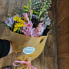 A beautiful assortment of seasonal flowers wrapped in tissue paper with greens