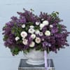 A stunning arrangement featuring delicate lilac blooms and vibrant ranunculus flowers.This arrangement