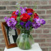 Clear vase filled with 6 Red Roses, fragrant purple stock, statice, and