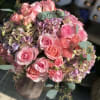 Gold glass cylinder nicely arranged with roses and hydrangeas accented with small