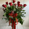A dozen long stems red roses with red ribbon and greenery in