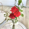 one rose and two carnations with greenery in small vase. 