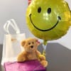 Classic teddy bear with a mylar balloon attached and a large box