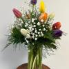 A dozen assorted tulips in a vase with baby&#039;s breath
