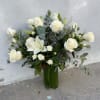An elegant arrangement in tall glass vase with white white roses, lilies