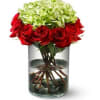 Red roses surrounding white hydrangea in a quality clear glass vase