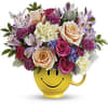 colorful roses and blooms in a smiling ceramic mug