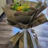 Red Roes, Sunflowers and greenery wrapped in brown floral paper in vase.