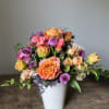 This vibrant floral arrangement is a celebration of seasonal exuberance, featuring a