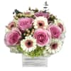 a seasonal arrangement of flowers in a wooden box with blush hues