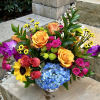 A ceramic pot of flowers that includes sunflowers, roses, spray roses, gladiolus