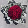 50 red roses wrapped in babies breath and paper tied with bow.