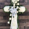 An elegant funeral cross designed in all white, including roses, carnations and