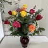 One dozen assorted color roses beautifully arranged in a glass vase