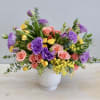 This cheerful arrangement combines bright blooms of yellow, pink, and lavender! A