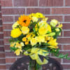 Sunny yellow roses, mums and lilies rise from a clear vase &mdash;