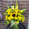 Sunny yellow roses, mums and lilies rise from a clear vase &mdash;