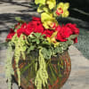 Red roses and orchids arranged in a keepsake glass half-moon vase designed