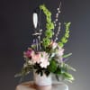 A gorgeous sympathy arrangement with a small hanging wind chime keepsake with
