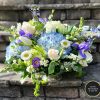 A large centerpiece made of blues and whites of roses, hydrangeas, iris