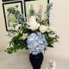 This stunning floral arrangement features a sophisticated blend of blue and white
