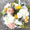 Peach roses, hydrangeas, solidago and other flowers in clear glass vase