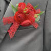 This all red pocket square features red ranunculus, red spray roses, and