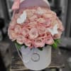 A pink box filled with pink roses. Decorated with pearls and gold