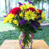 Red carnations, yellow daisies, purple Monte Casino blooms and green button poms