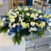 Casket spray arrangement with white roses, lilies, mums, carnations, blue delphinium, fillers