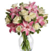 A stunning vase of pink lilies, white roses, and variegated pittosporum greenery.