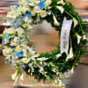 This is a beautiful funeral wreath with white lilies, roses, chrysanthemums, and